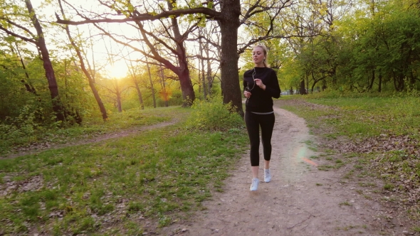 Jogging In Spring Forest. Woman Running In The Forest, The Sun Is Shining It In The Back