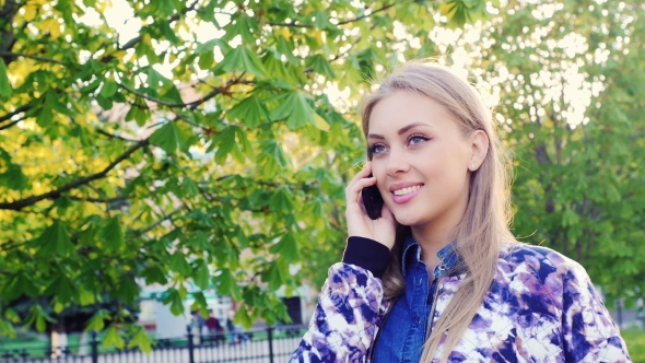 Young Woman Walking In The Park, Talking On The Phone