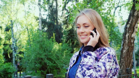 Young Woman Walking In Spring Park, Talking On a Cell Phone