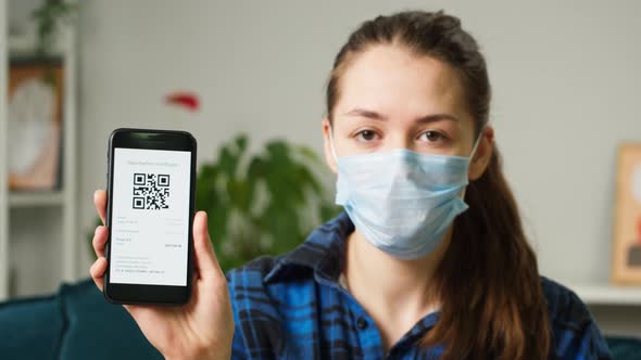 Woman Wearing Medical Mask Showing on Phone Vaccination Passport with Qr Code International