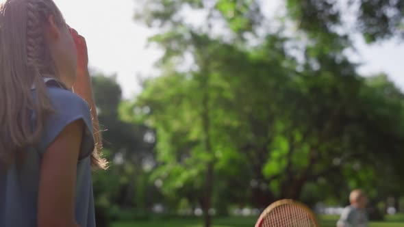 Bored Girl Play Badminton with Brother Touching Racket Net in Park