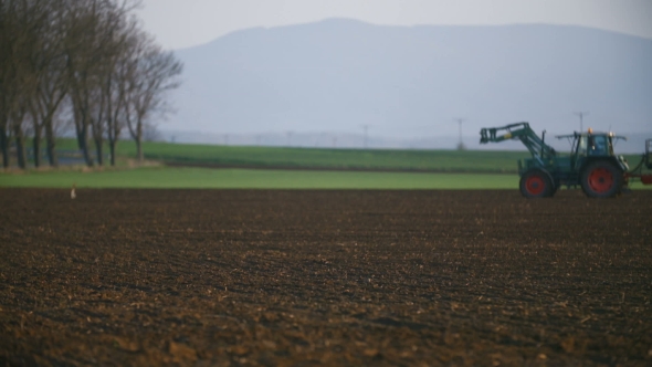 Tractor Working in the Field at Sunset