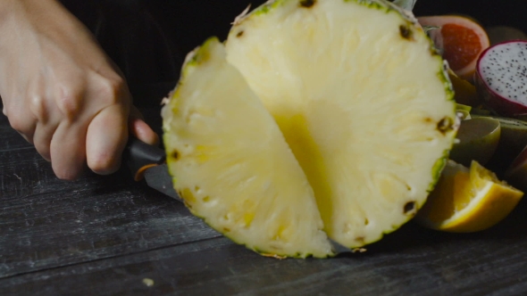 Chef Slicing Pineapple On Black Background