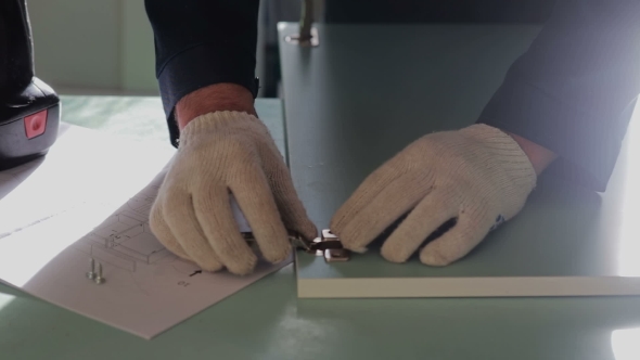 Man Assembles Furniture Using a Power Screwdriver