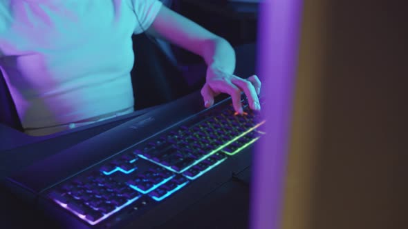 Young Concentrated Gamer Woman Sits at the Computer in the Gaming Club and Playing Shooter Game