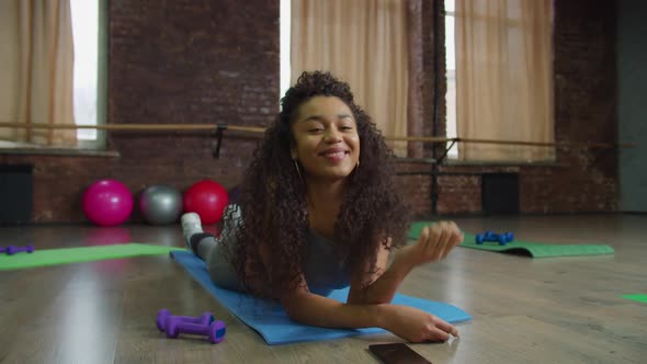 Smiling Black Female Lying on Fitness Mat Indoors