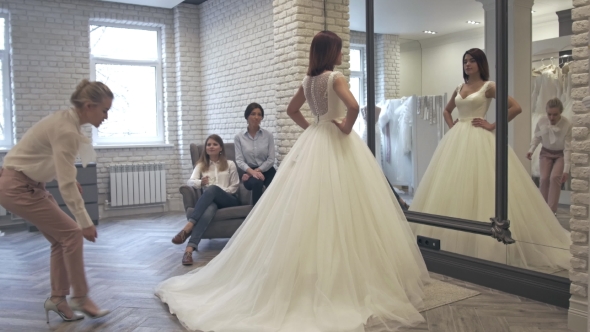 Women Having Fun During Bridal Gown Fitting In Wedding Fashion Store