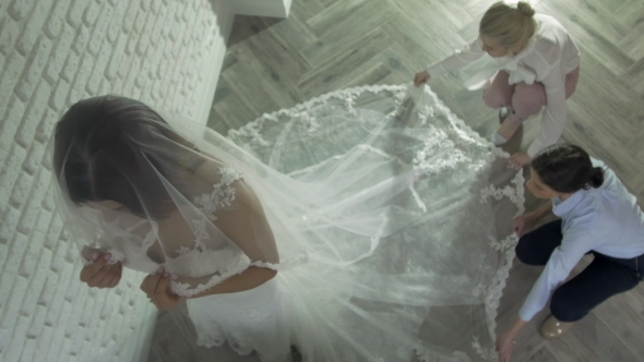 Women Making Adjustment To Wedding Gown In Professional Fashion Designer Studio