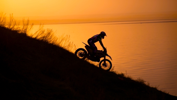 Motocross Bike Slides Down a Hill At Sunset