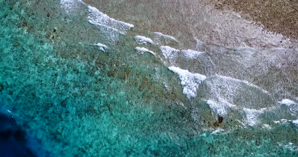 Wide aerial travel shot of a white sand paradise beach and blue water background in colourful 4K