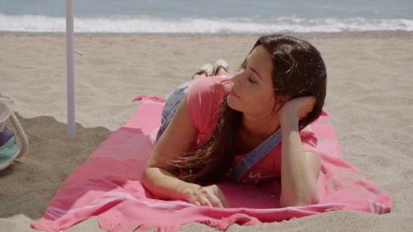 Young Lady Laying Down On Beach Blanket