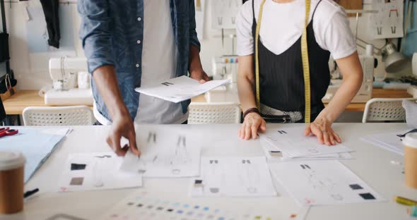 Clothes Designers Working with Sketches Putting Papers on Table Pointing