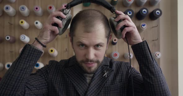 Man Putting on Headphones Nodding Head with Closed Eyes Then Looking at Camera