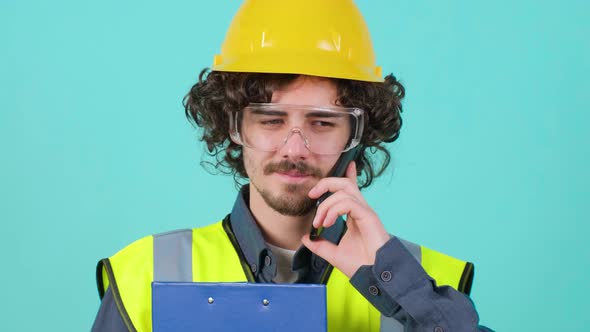 Construction Worker with Safety Glasses and Helmet That is Talking on Mobile Phone