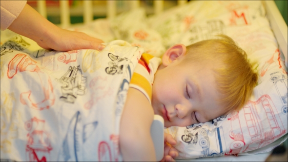 Mother Covering Sleeping Boy With Blanket