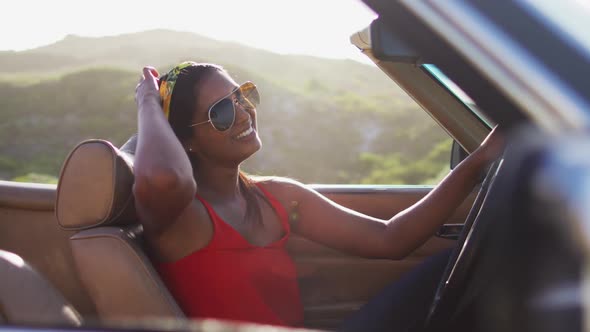 Portrait of african american woman sitting in the convertible car on road