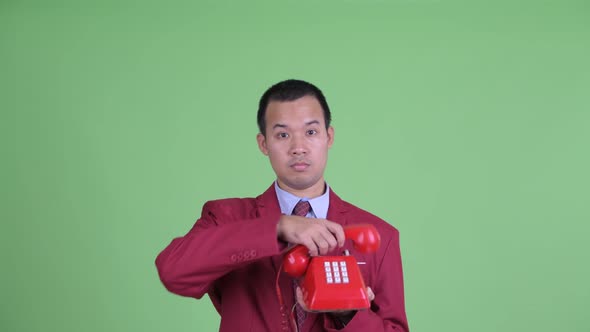 Face of Happy Asian Businessman Using Telephone and Looking Surprised