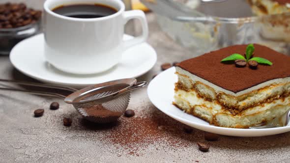 Traditional Italian Tiramisu dessert in glass baking dish and portion on grey concrete background