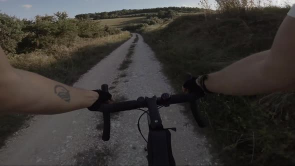 Biker riding downhill on dust road, Marche, Italy