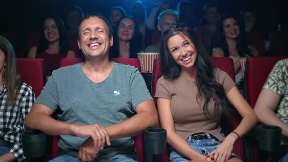 Happy Hispanic Couple Laughing Watching Comedian Movie at Cinema Sitting on Armchair in Row