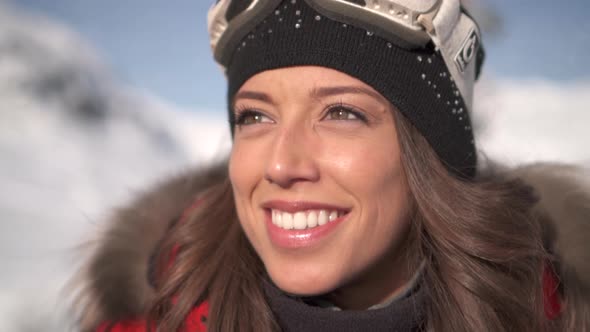 Portrait of a woman smiling lifestyle in the snow at a ski resort with goggles and beanie hat