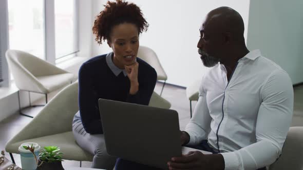 Diverse male and female business colleagues talking, man using laptop in office