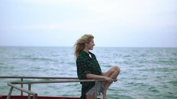 Young Woman with Long White Hair Sitting on a Boat Staring at Horizon with Smile