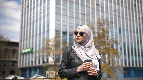 Portrait of Young Stylish Muslim Business Woman in Hijab and Sunglasses Outdoors with Cup of Coffee