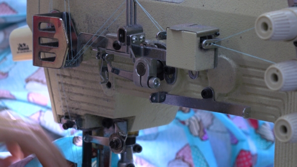 Factory Seamstress At Work And Industrial Sewing Machine