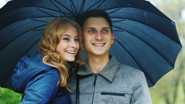 A Young Couple Standing Under An Umbrella
