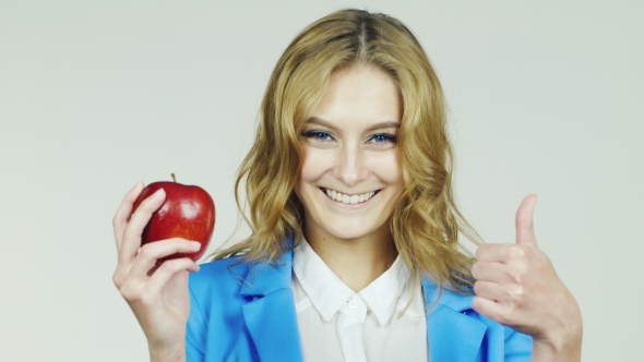 Girl With Red Apple In His Hand Showing Approval Gesture With Thumb Up