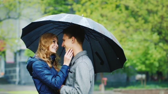 Stylish Young Couple Embracing Under An Umbrella