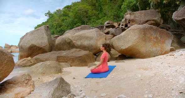 Woman Seats in Meditation Pose She is on the Beach By the Sea Line Against Tropical Forest
