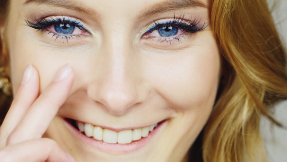 Portrait Of a Young Blue-eyed Woman Stroking Her Face With His Fingertips