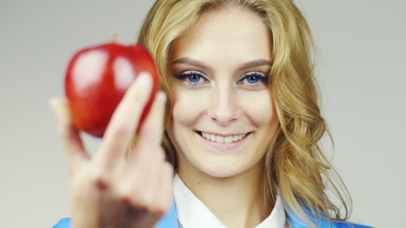 Portrait Of Attractive Blue-eyed Woman Holds Up a Red Apple