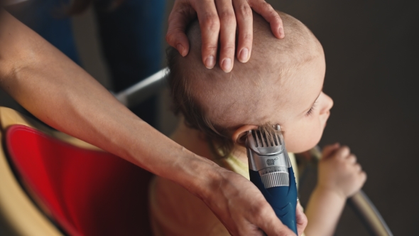 Mother Doing a Haircut For a Baby Boy With a Hair Clipper