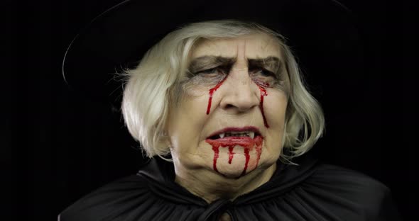 Old Witch Halloween Makeup. Elderly Woman Portrait with Blood on Her Face.