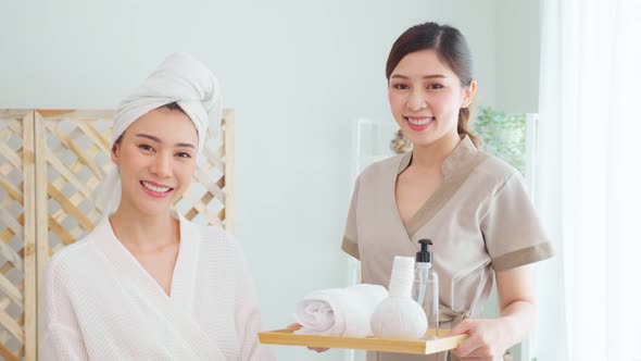 Portrait of Asian young masseuse woman and client looking at camera.