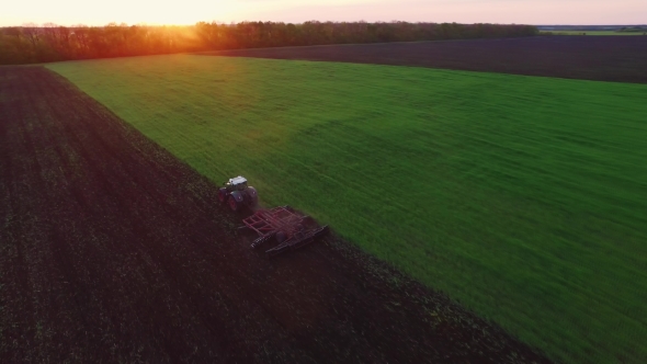 Tractor Plowing The Field At Sunset