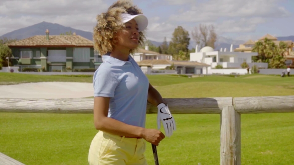 Attractive Young Woman Golfer Leaning On a Fence
