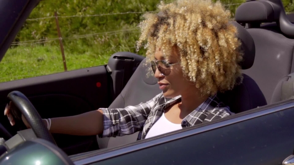 Trendy Young Woman Driving a Sports Car