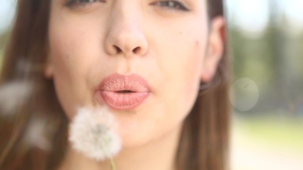 Woman Blowing On A Dandelion Close-Up