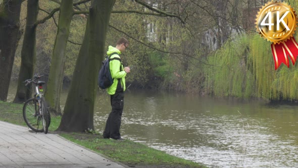 Man is Looking at River Clicks a Tablet Bicycle