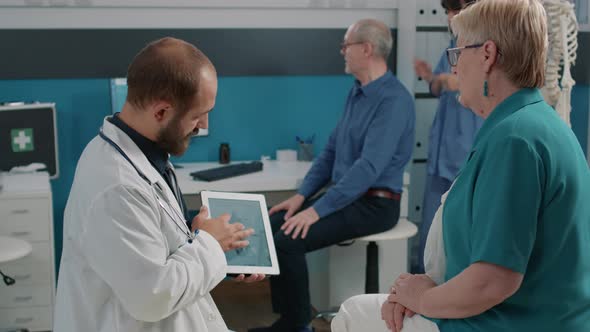 Male Osteopath Showing Human Skeleton Illustration on Tablet