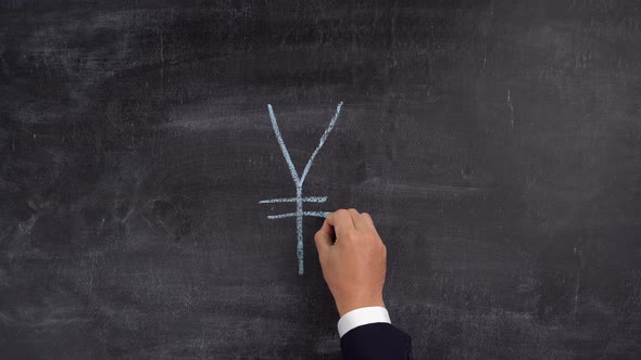 A businessman's hand draws a symbol of the yen, the Japanese currency, on a chalkboard
