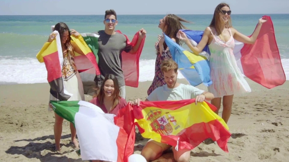 Group Of Friends On Beach With Football And Flags