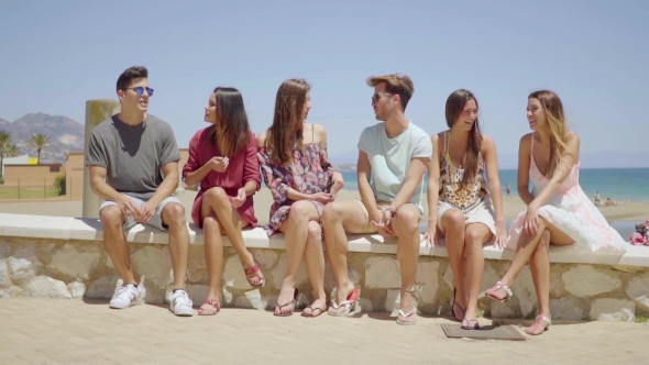 Young Teenage Friends In Shorts Talking Near Beach