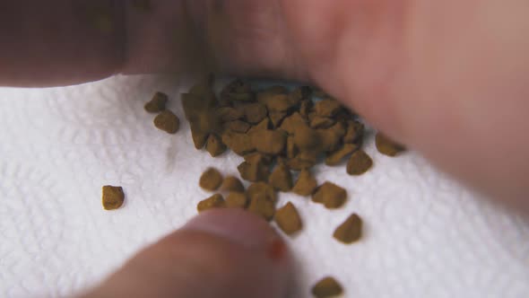 Person Pours Brown Instant Coffee Granules Onto Paper Napkin