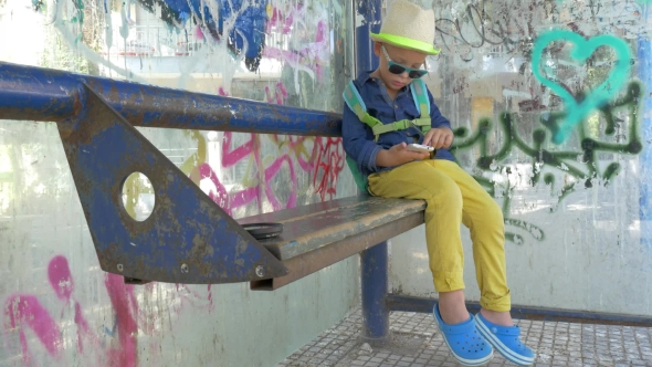 Child Using Smart Phone On Grungy Bus Stop