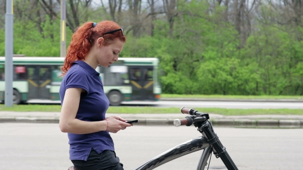 Girl Sitting on the Bike and Texting on Smartphone